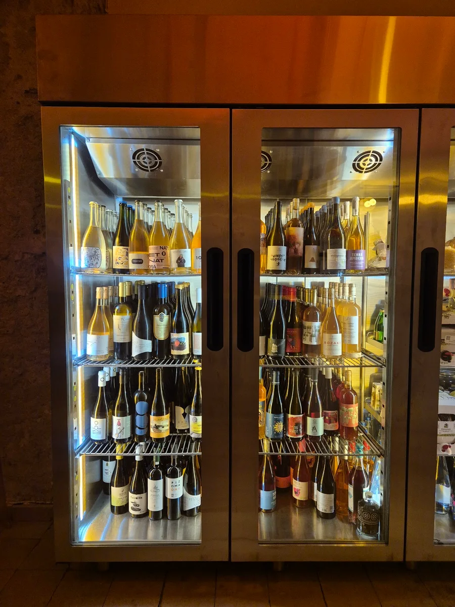 A lit display wall of Greek wine bottles at a Thessaloniki wine bar