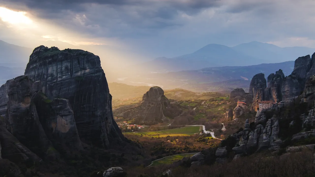 The Meteora valley at golden hour, monasteries perched on towering rock pillars near Kalambaka