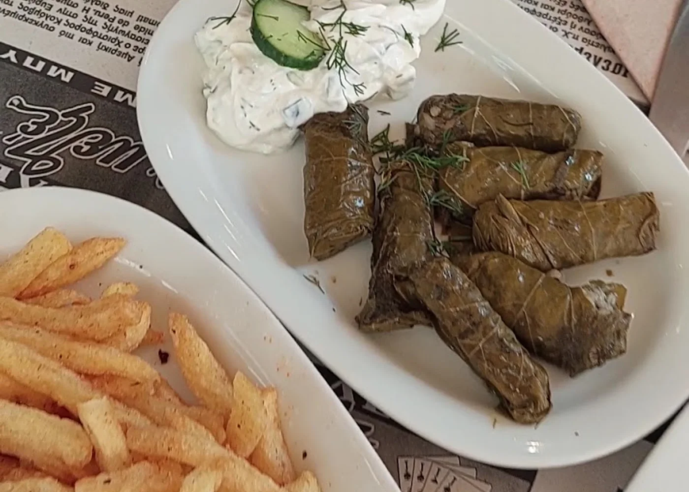 A meze spread of dolmades, tzatziki and fried potatoes on a Greek taverna table