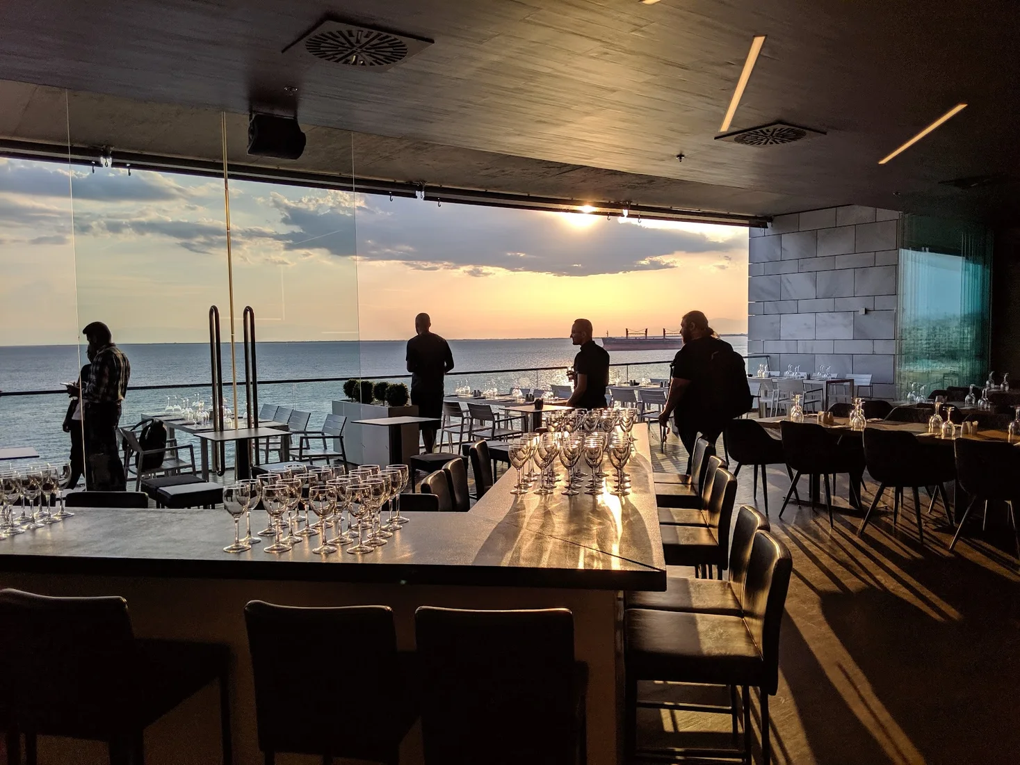The glass-walled bar and sea-view terrace of Allegro at sunset on the Nea Paralia waterfront, Thessaloniki