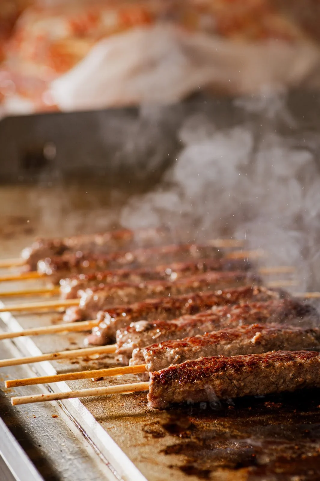 Pork souvlaki skewers grilling over charcoal at Athinaikó Souvlaki, central Thessaloniki