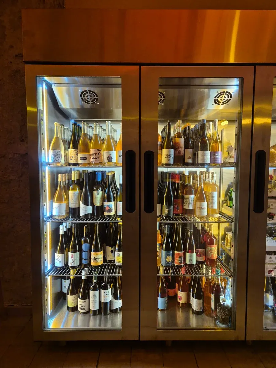 A lit display wall of Greek wine bottles at a Thessaloniki wine bar