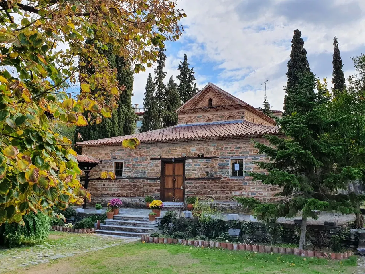 The modest stone exterior of the 14th-century church of Agios Nikolaos Orfanos in its Ano Poli garden, Thessaloniki
