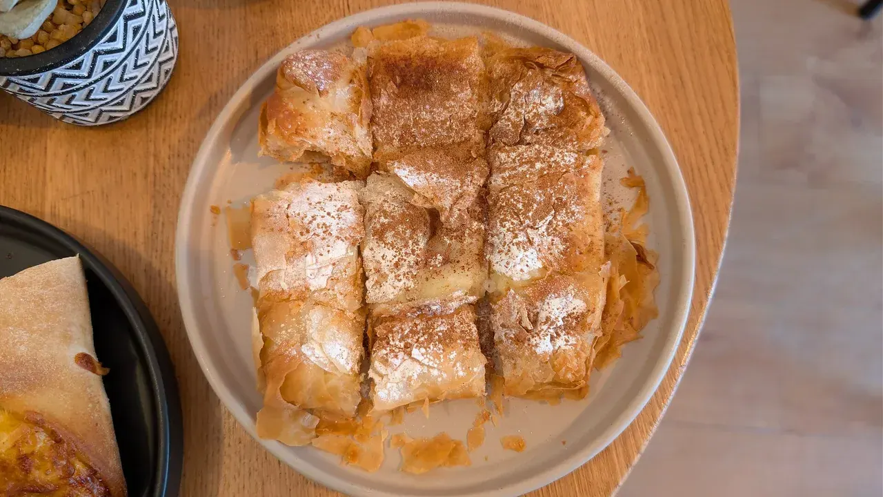 A plate of golden bougatsa squares dusted with sugar and cinnamon, Thessaloniki