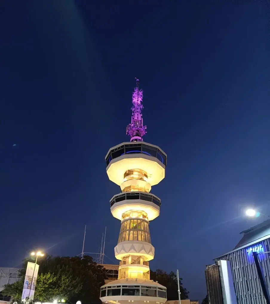 The tiered OTE Tower lit gold against the night sky at the Thessaloniki international fairgrounds