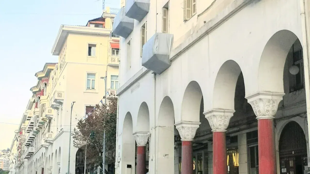 A red-columned arcaded street in central Thessaloniki near Aristotelous Square, busy with pedestrians