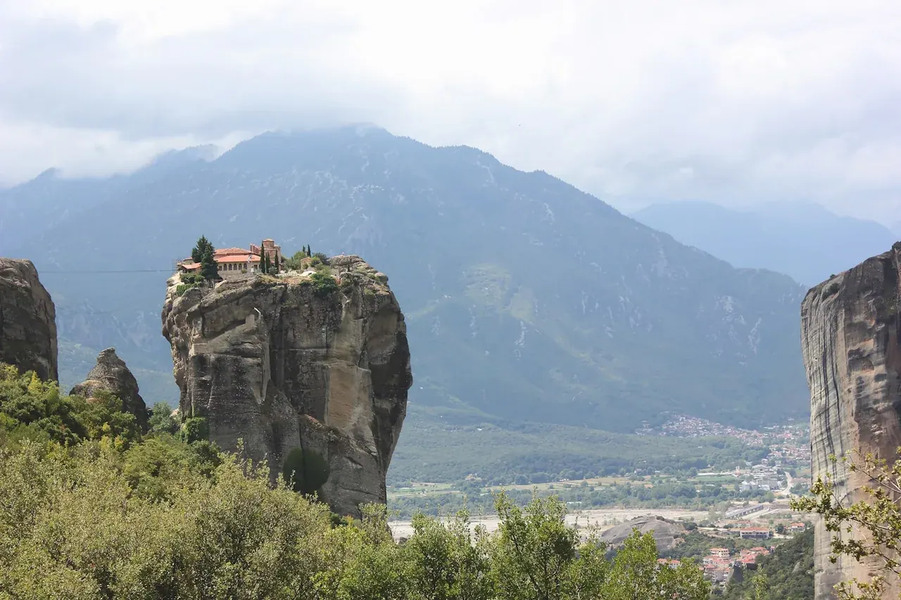 The Holy Trinity Monastery on its sheer pinnacle at Meteora, mountains beyond