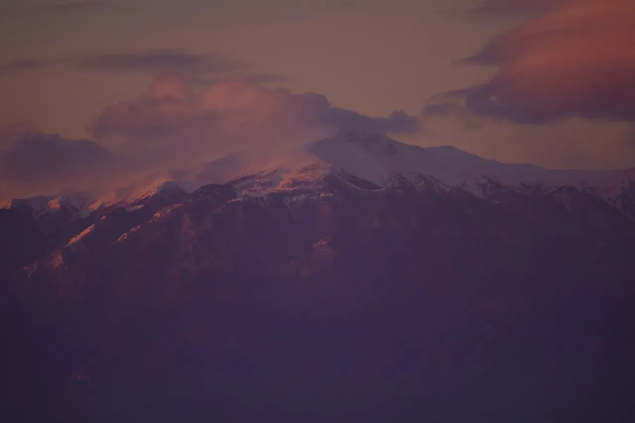 The snow-capped summit of Mount Olympus glowing pink at sunset