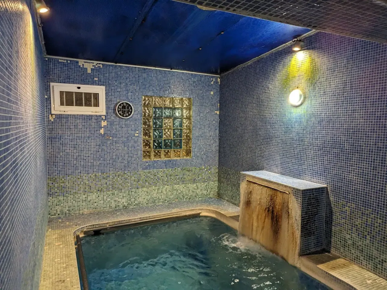 An indoor stone thermal bath pool with mood lighting at Loutra Pozar