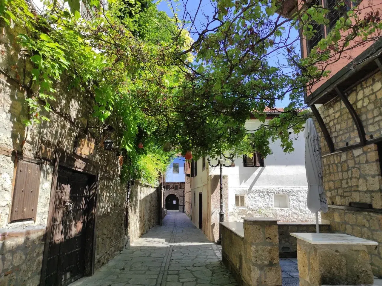 A vine-shaded cobbled lane between stone houses in Veria's old town