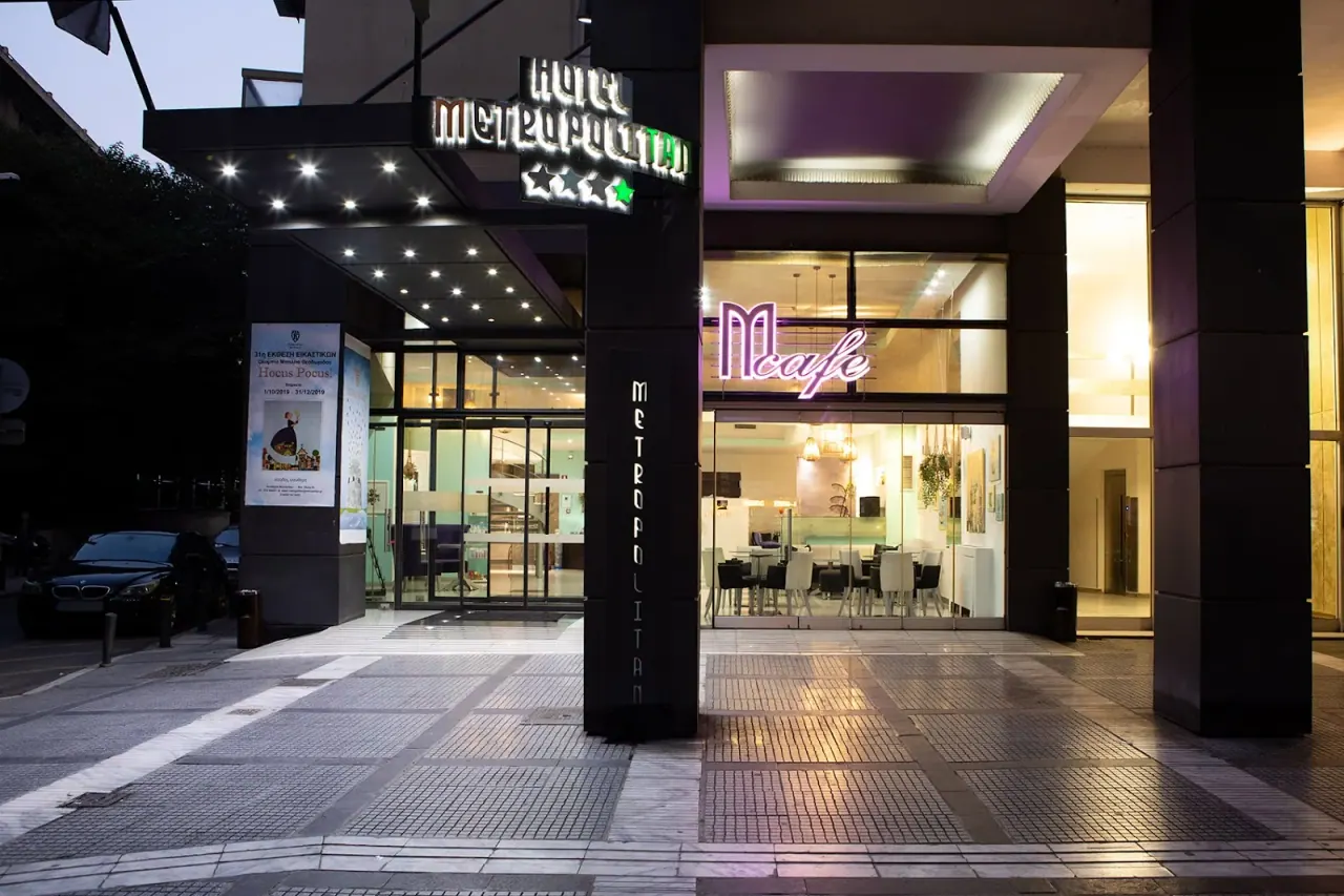 Illuminated entrance of the Metropolitan Hotel with its neon sign and the M café at dusk