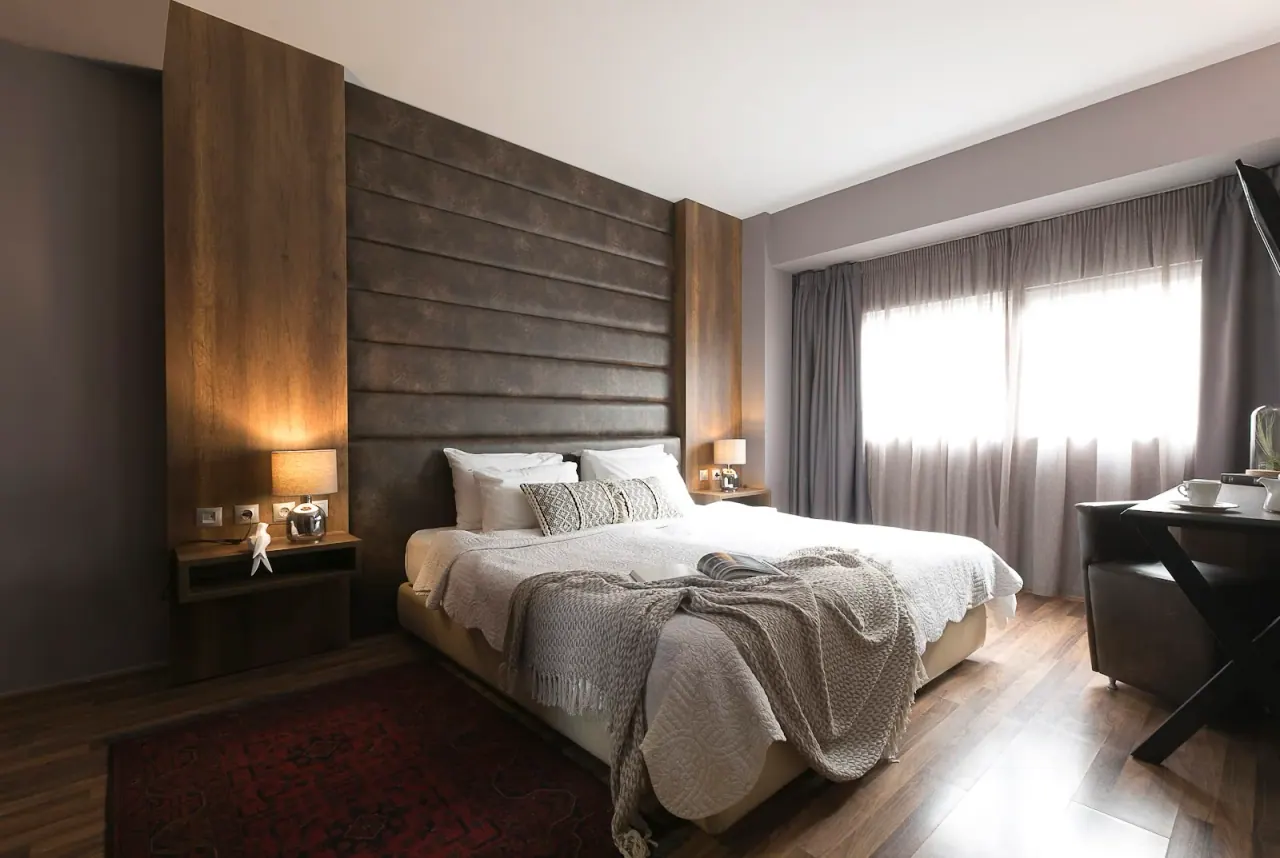 A warm-toned room with a wood-panelled headboard wall at Hotel Plaza Thessaloniki