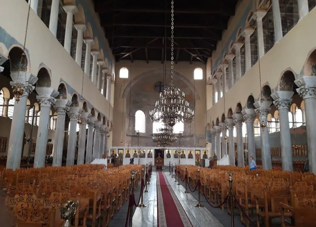 The colonnaded nave of the Acheiropoietos basilica under its timber roof, lined with marble columns and carved capitals toward the templon, Thessaloniki