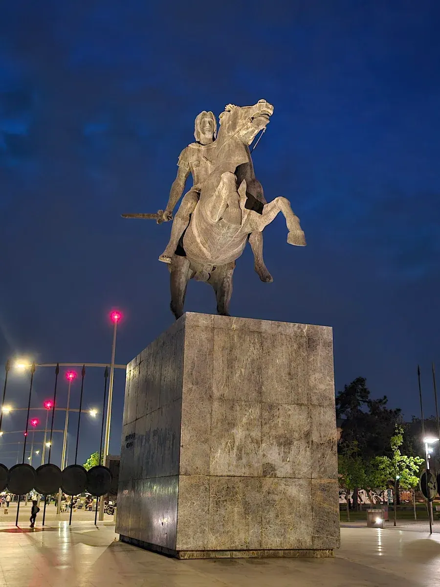 The Alexander the Great statue floodlit against a deep-blue dusk sky on the Thessaloniki waterfront