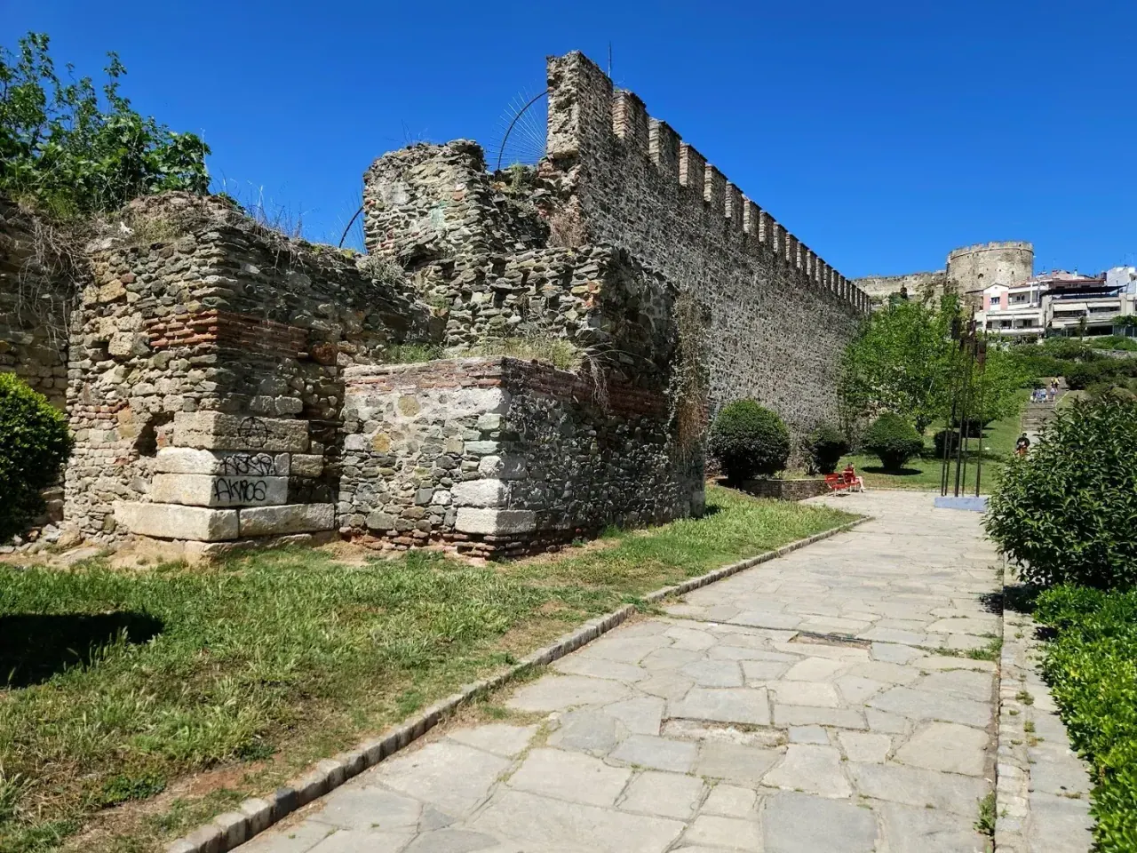 A sunlit stretch of the Byzantine land walls of Thessaloniki with a walking path alongside