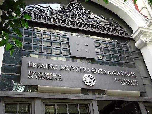 The trilingual entrance sign of the Jewish Museum of Thessaloniki — Greek, English and Ladino ('Museo Djudio de Salonik') — with the menorah emblem