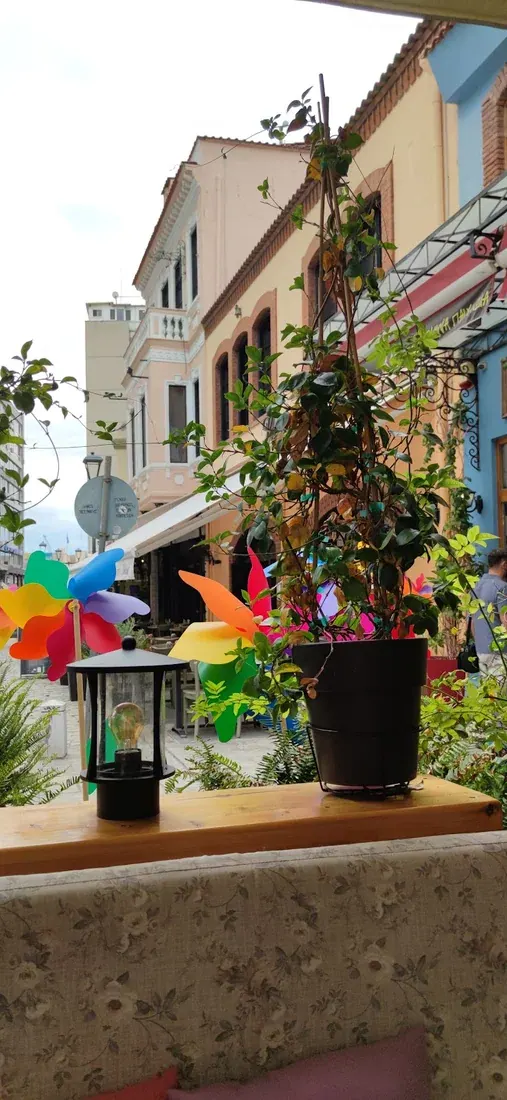 A colourful café terrace looking onto a pastel-fronted pedestrian lane in the Ladadika district of Thessaloniki
