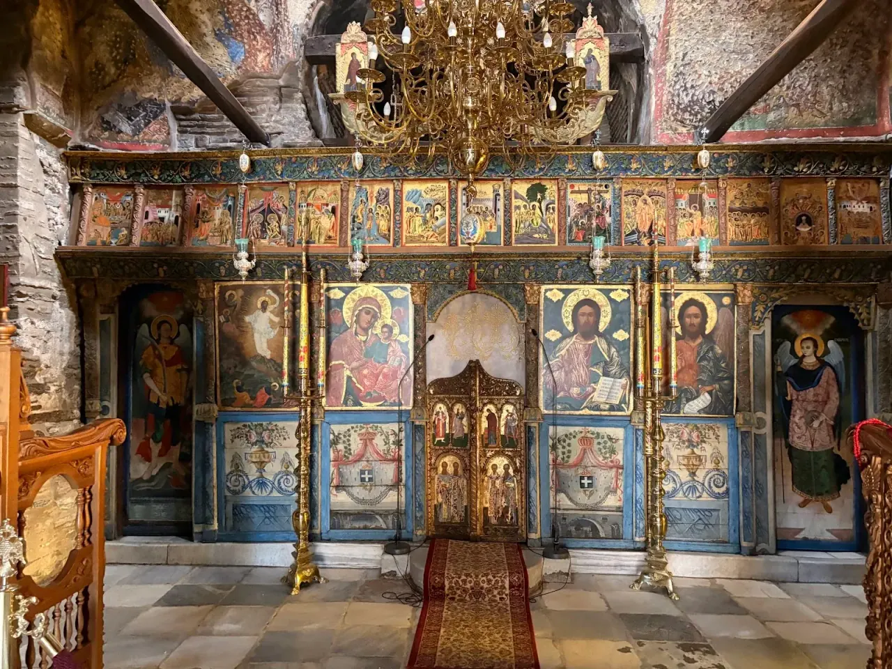 The painted and gilded iconostasis of the catholicon at Vlatadon Monastery, framed by Byzantine wall frescoes, Thessaloniki