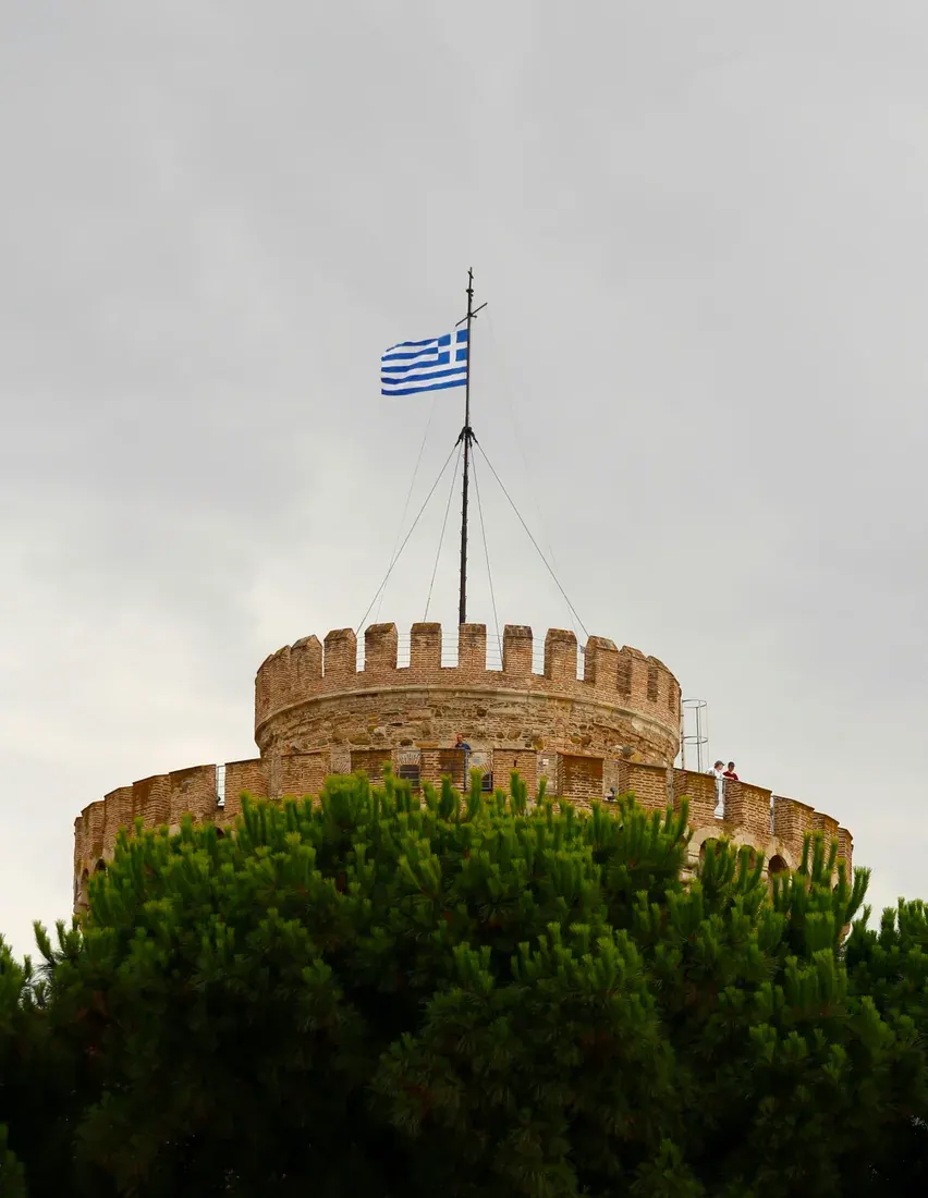The crenellated top of the White Tower flying the Greek flag