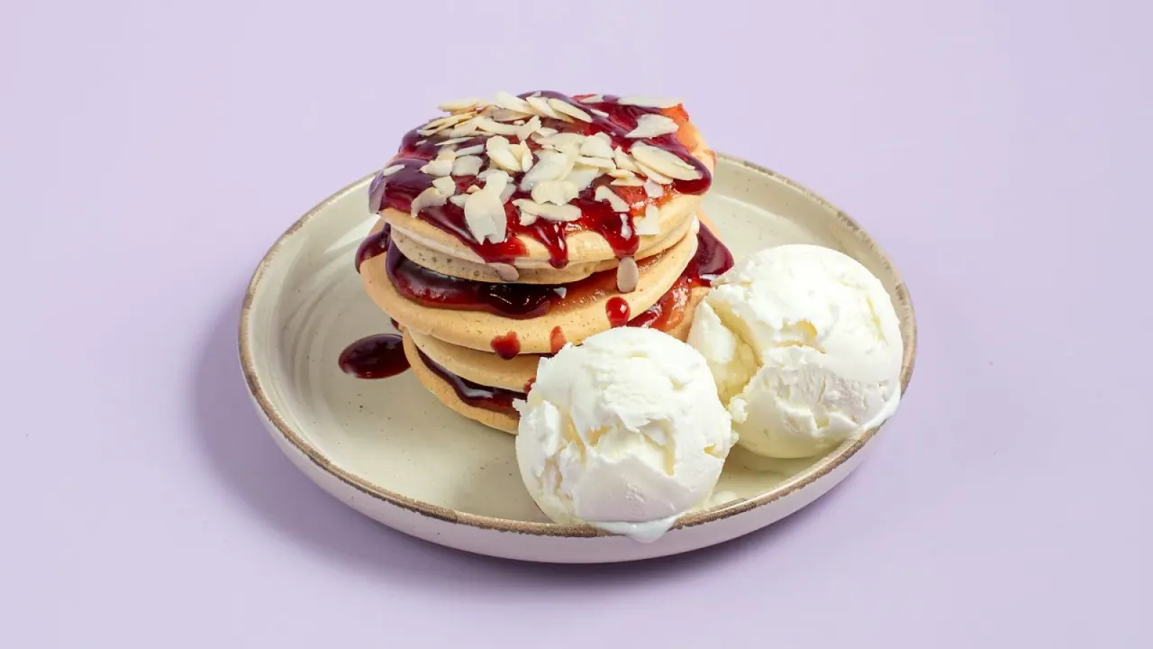 Pancakes with berry sauce, almonds and scoops of Aega's goat's-milk ice cream on a plate, Thessaloniki