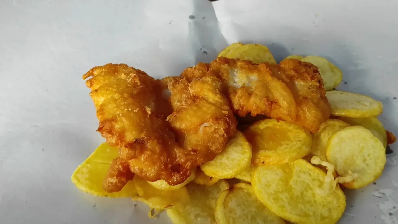 Battered fried cod fillets over chips on white paper at Bakaliarakia sto Limani, near the port, Thessaloniki