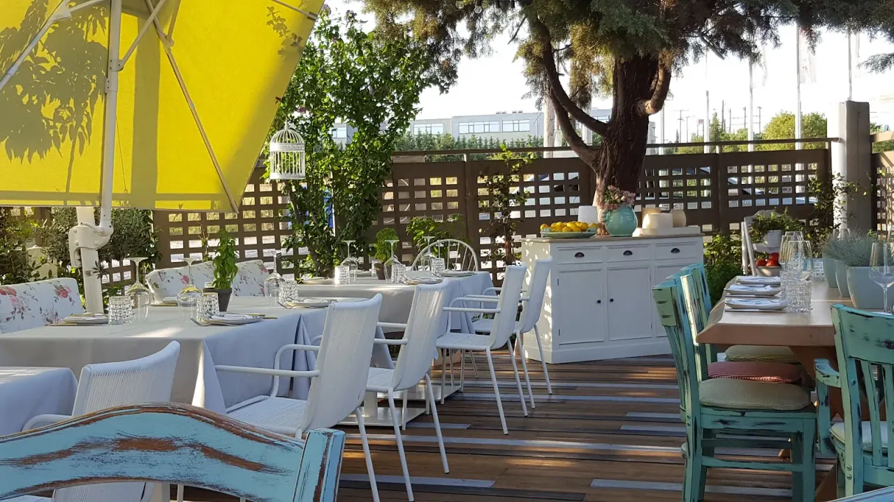 A garden terrace with a yellow parasol, distressed pastel chairs and lemon trees at Duck restaurant, Pilea, Thessaloniki