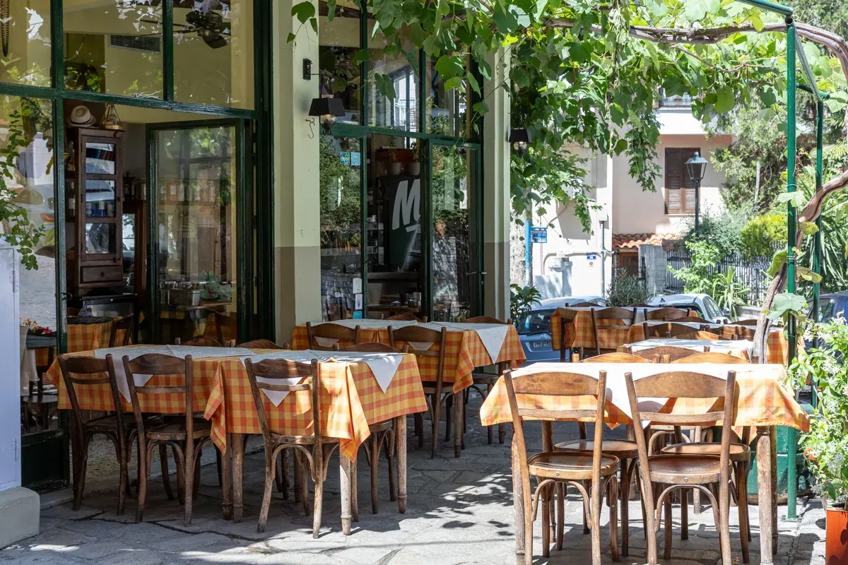 The vine-shaded terrace of Igglis taverna with orange gingham tablecloths and bentwood chairs, upper Thessaloniki
