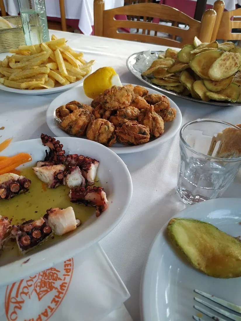 A shared spread of grilled octopus, fried mussels and fried courgette on Karnagio-branded plates, Ampelokipi, Thessaloniki