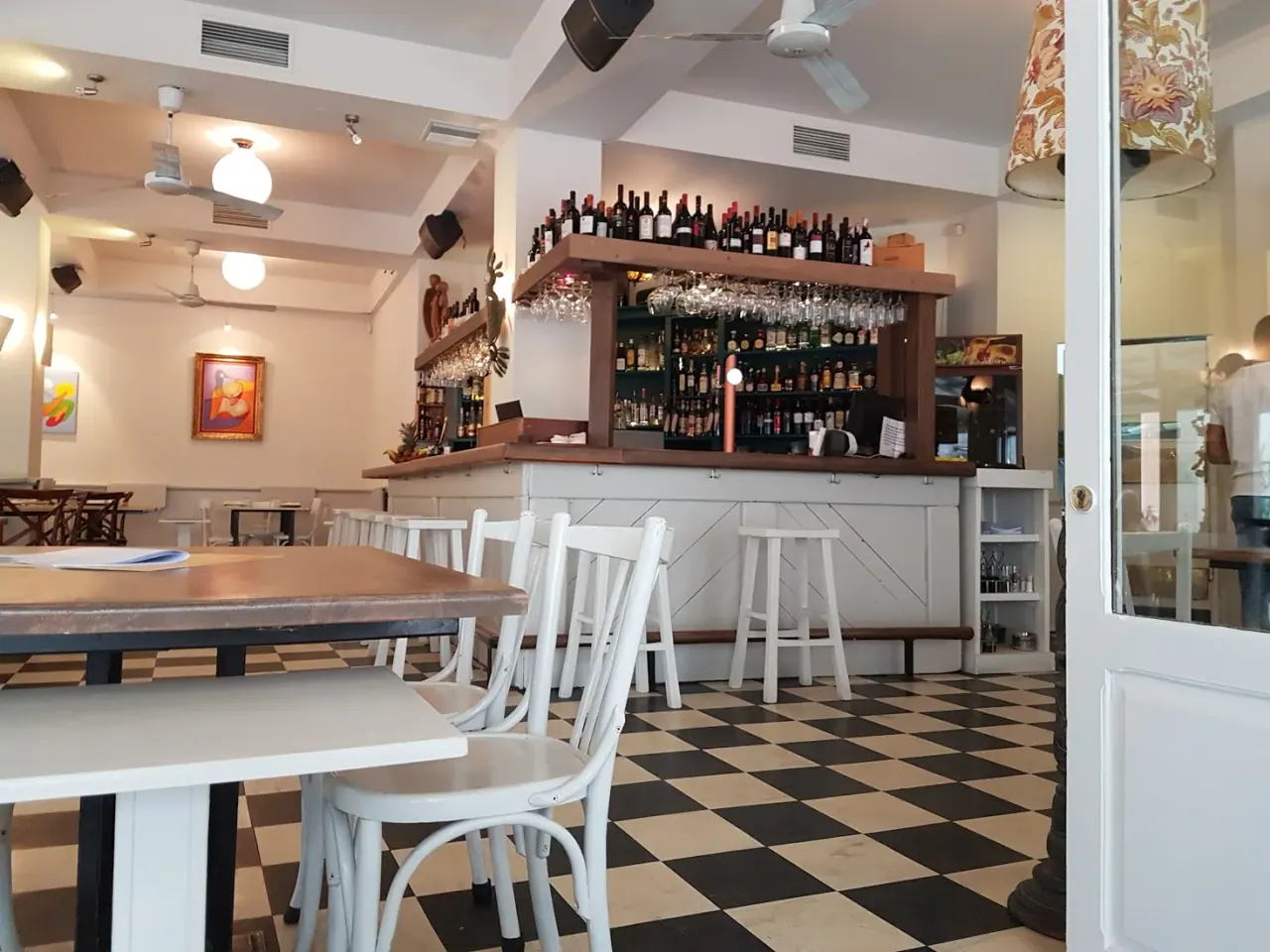 The eclectic interior of Paparouna with a black-and-white checkerboard floor and a stocked bar, near Valaoritou, Thessaloniki