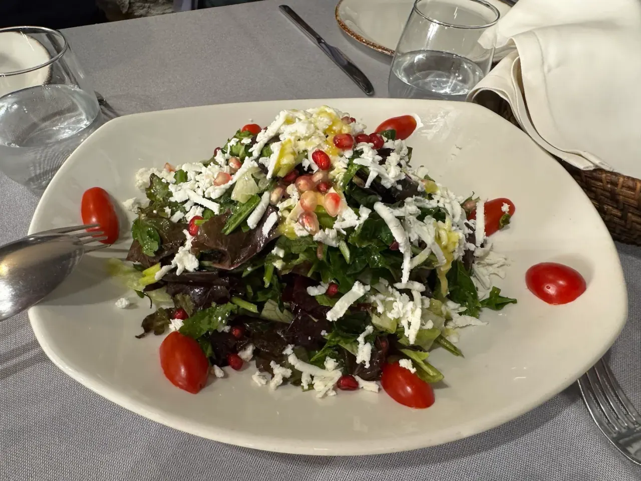 A green salad scattered with grated mizithra cheese and pomegranate seeds at Rodi & Meli, Thessaloniki