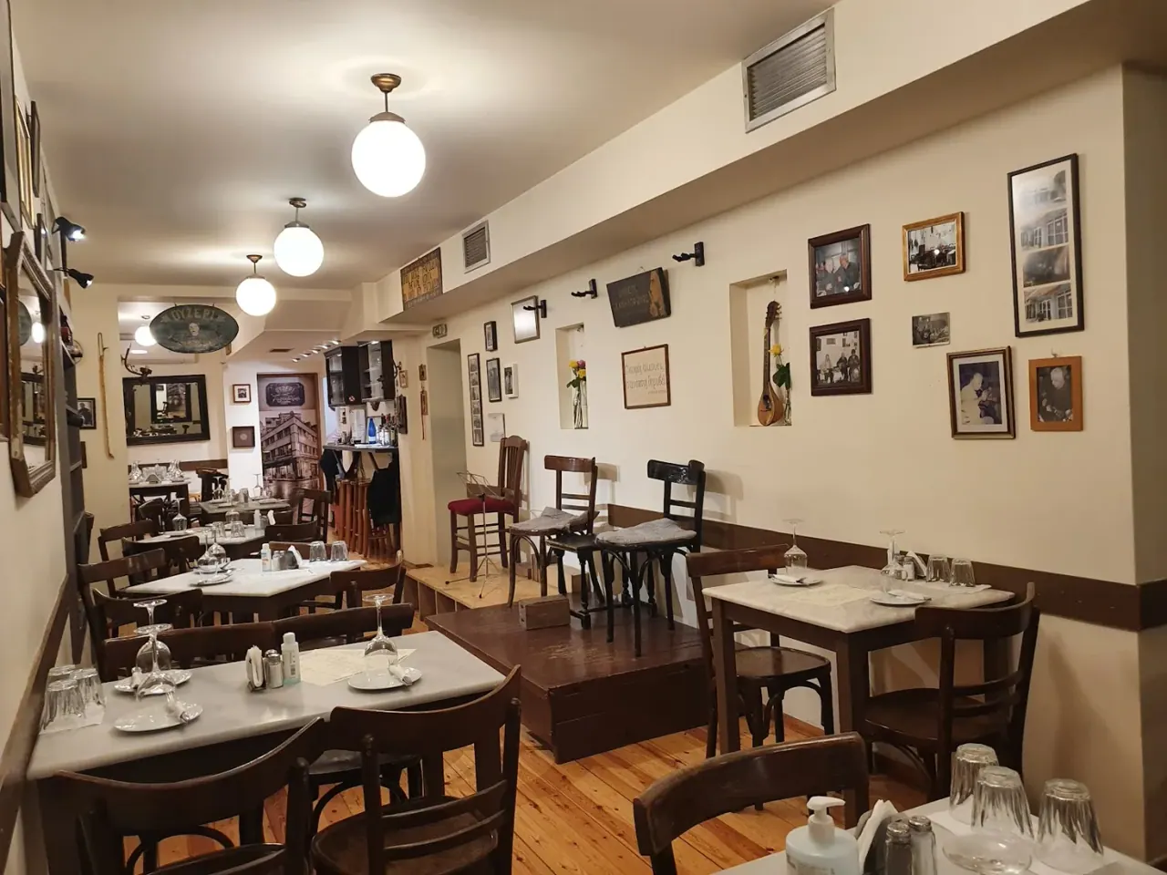 The cosy interior of Tompourlika hung with framed photographs above marble-topped tables, central Thessaloniki