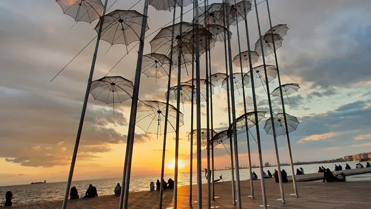 The sun setting through the Umbrellas sculpture on the Thessaloniki waterfront over the Thermaic Gulf