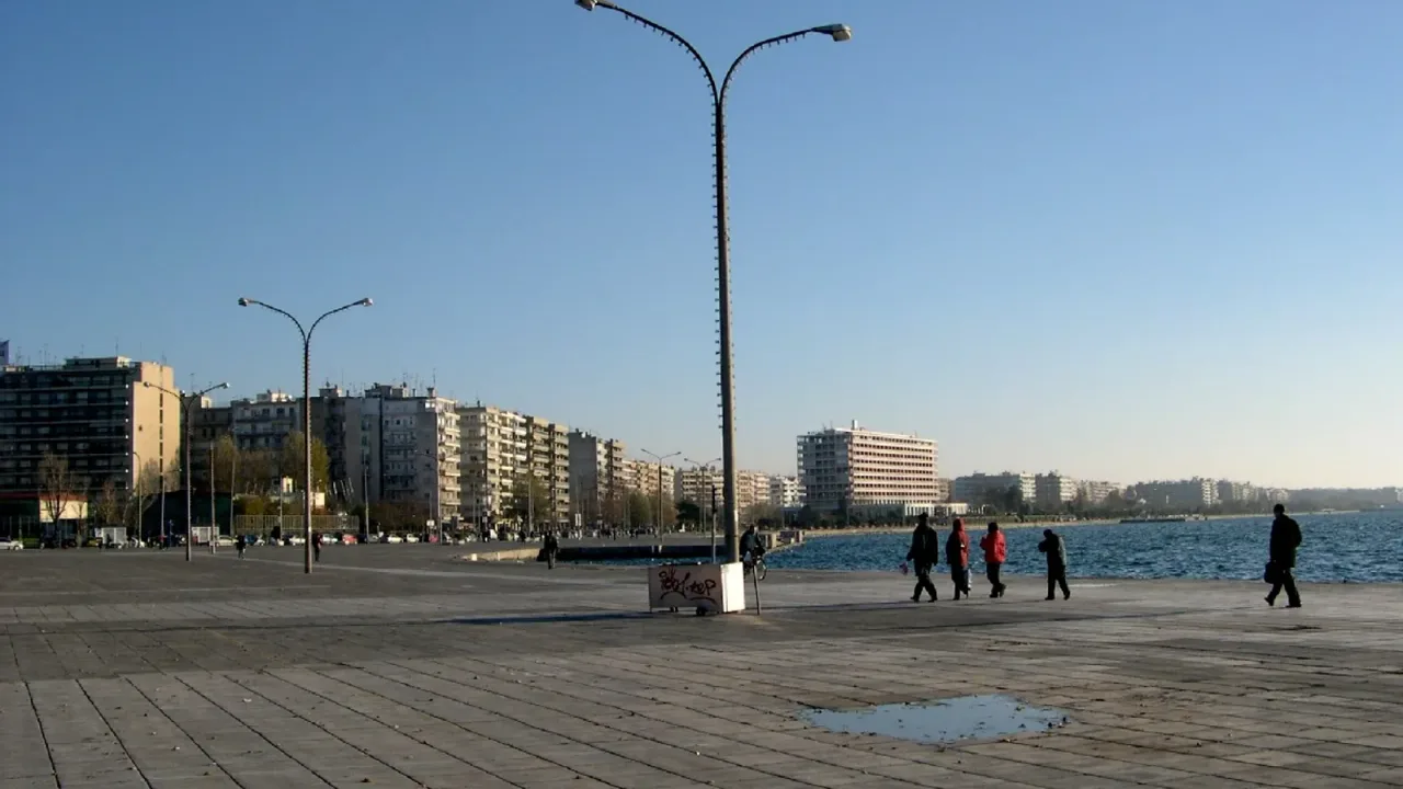 The Thessaloniki waterfront promenade along the Thermaic Gulf, with people walking and the city skyline behind