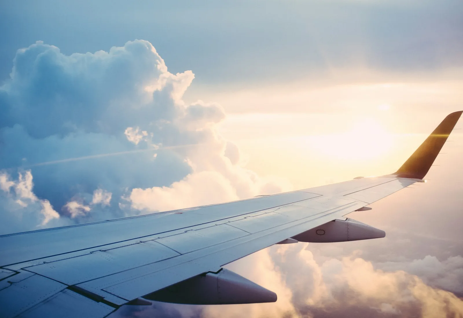An airplane wing above the clouds at sunset
