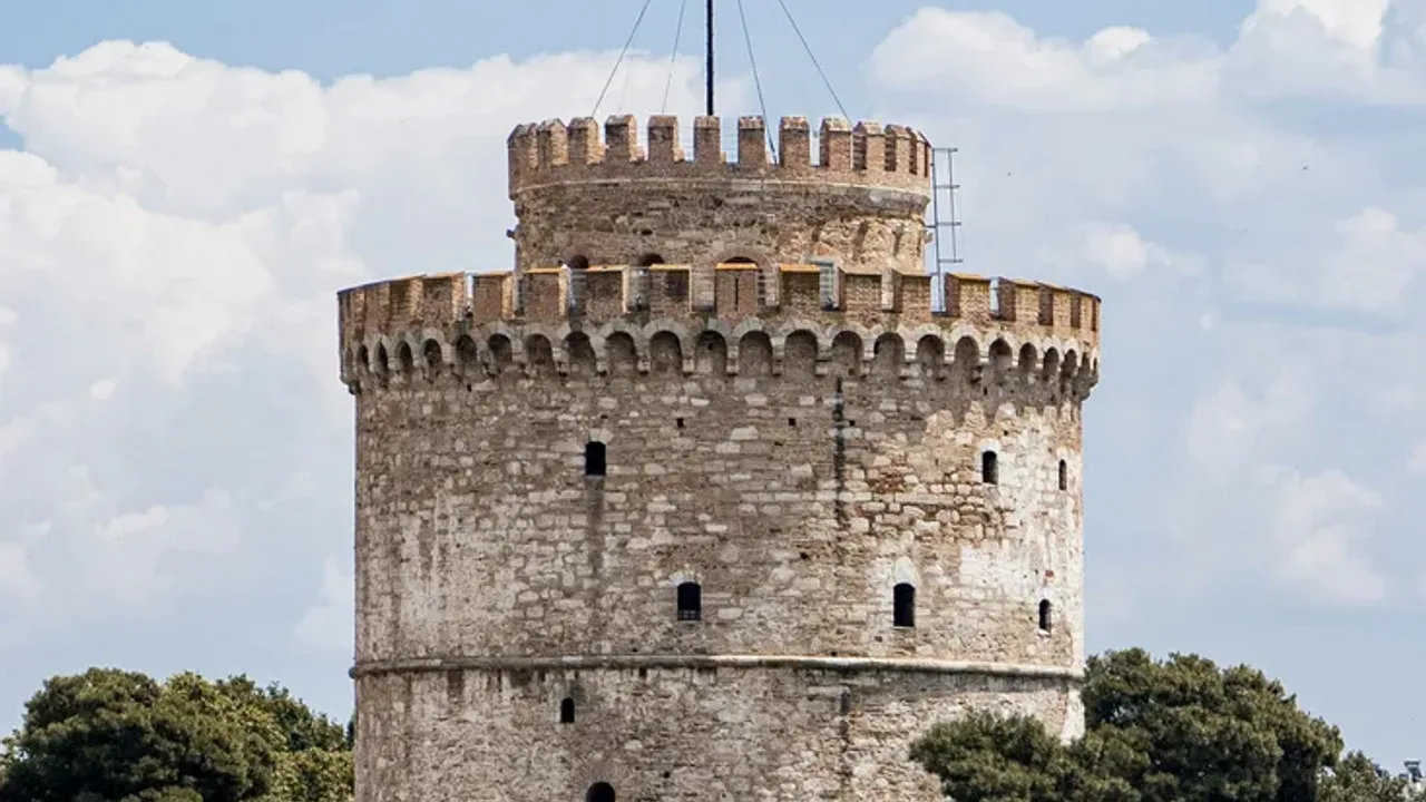 The cylindrical White Tower of Thessaloniki on the waterfront against a blue sky