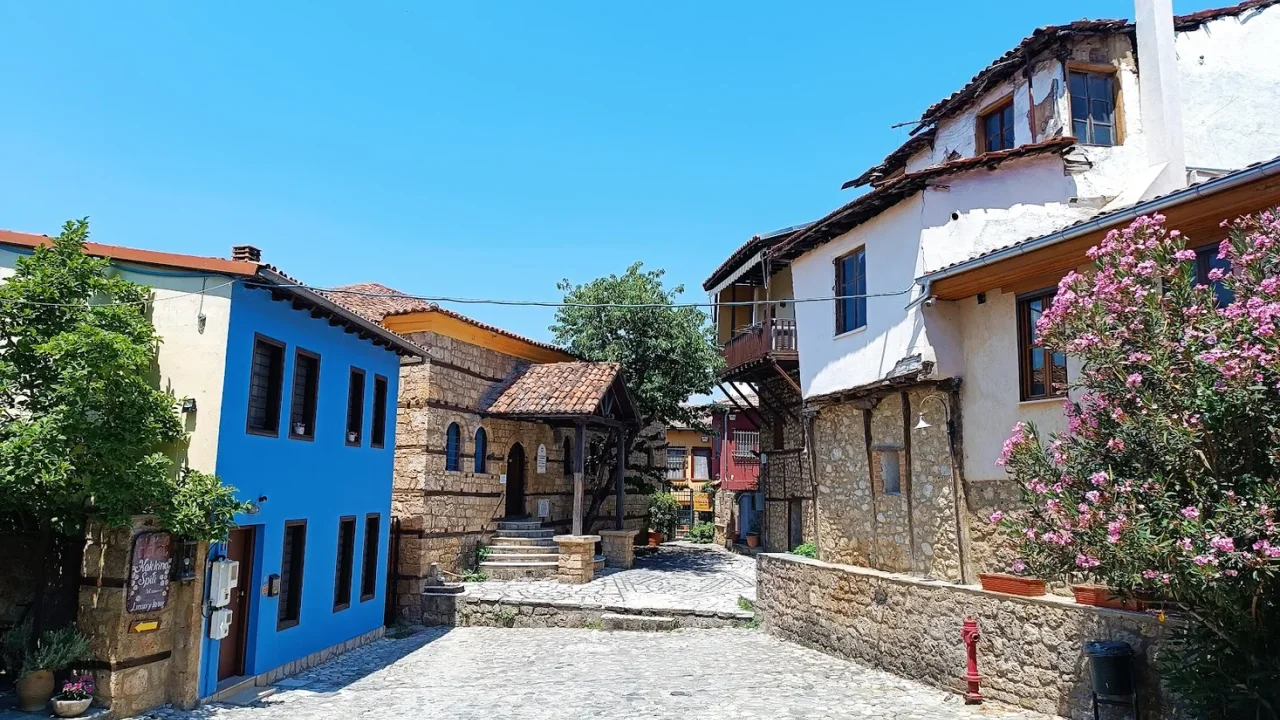 A cobbled square in Veria's old town with a blue mansion, a stone church and pink oleander