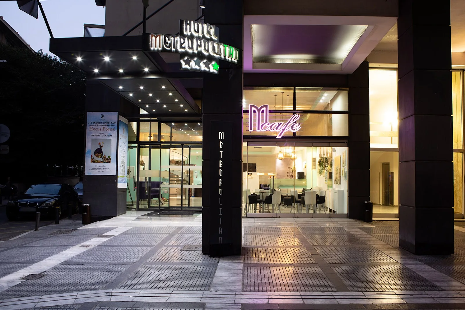 Illuminated entrance of the Metropolitan Hotel with its neon sign and the M café at dusk