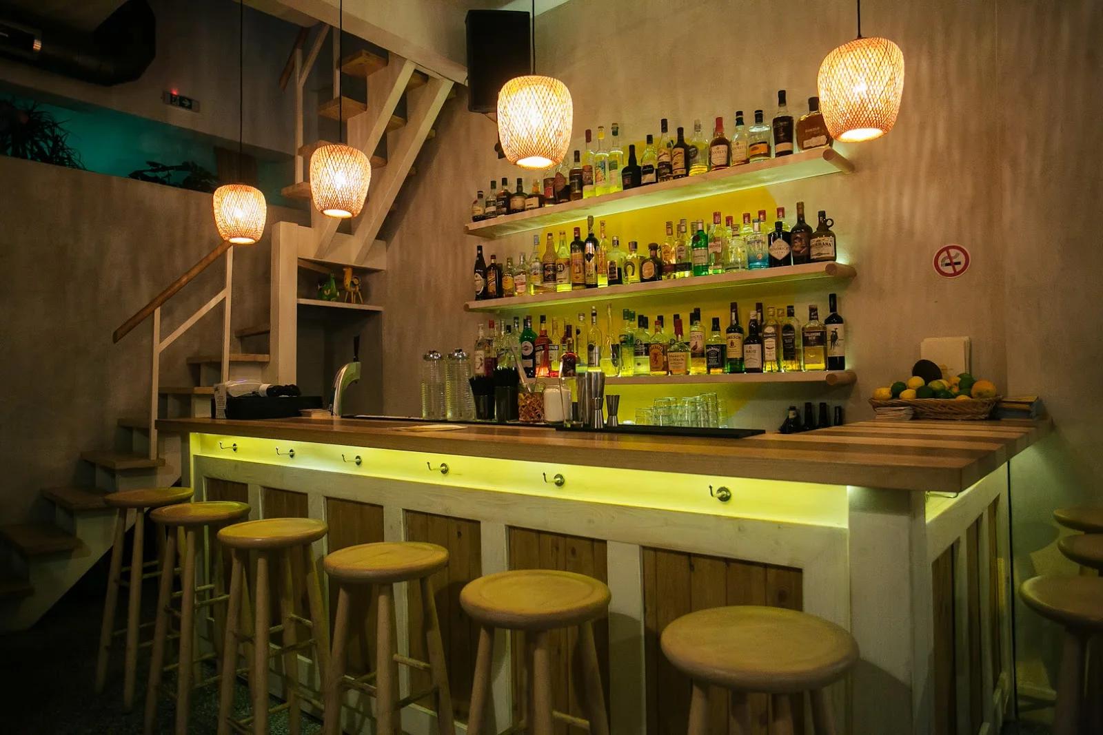 The backlit spirits shelves and bamboo pendant lamps above the wooden bar at Baobab in Ano Ladadika, Thessaloniki