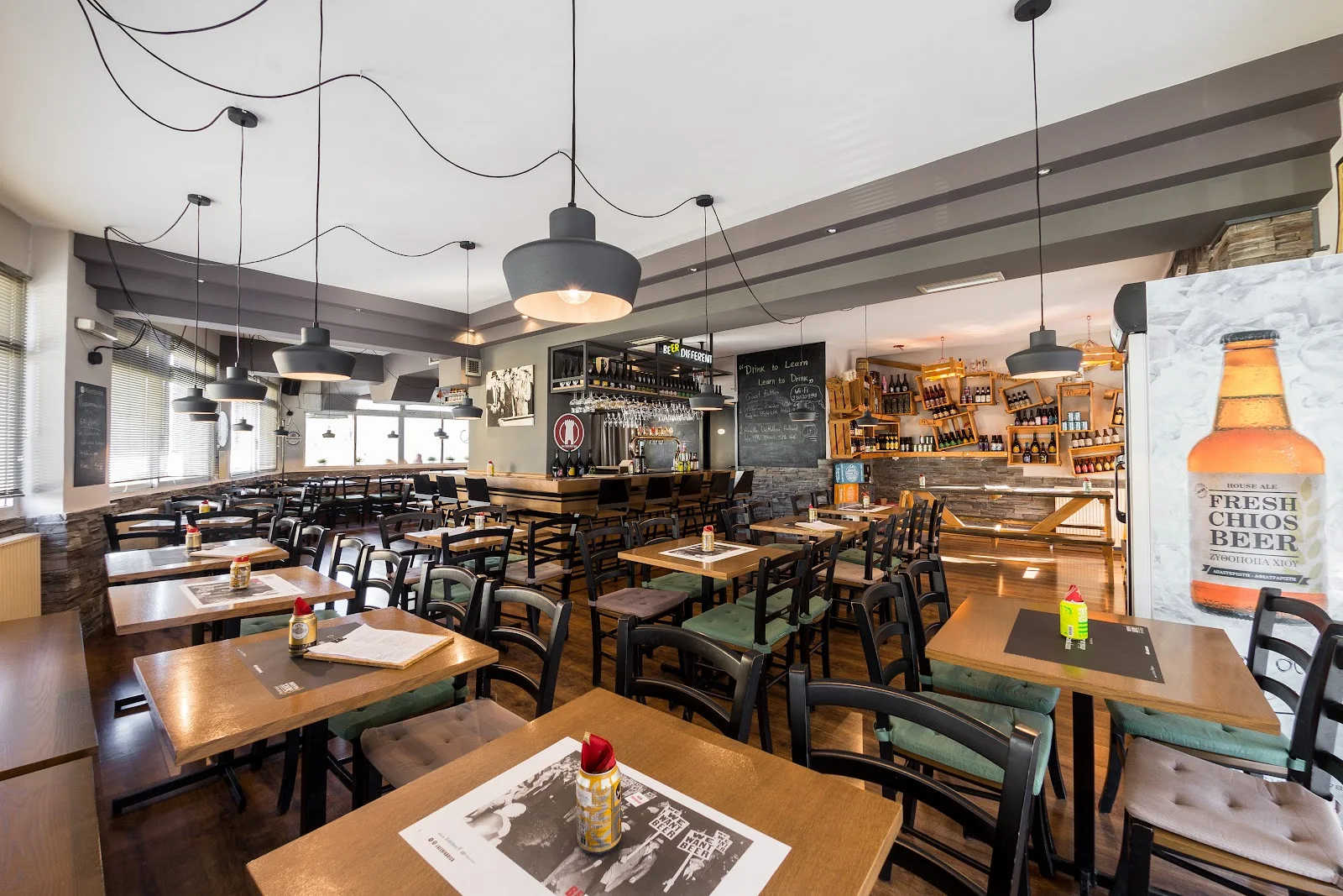The bright, wood-lined interior and bottle-lined bar of Beer Fabrica craft-beer taproom in Sykies, Thessaloniki