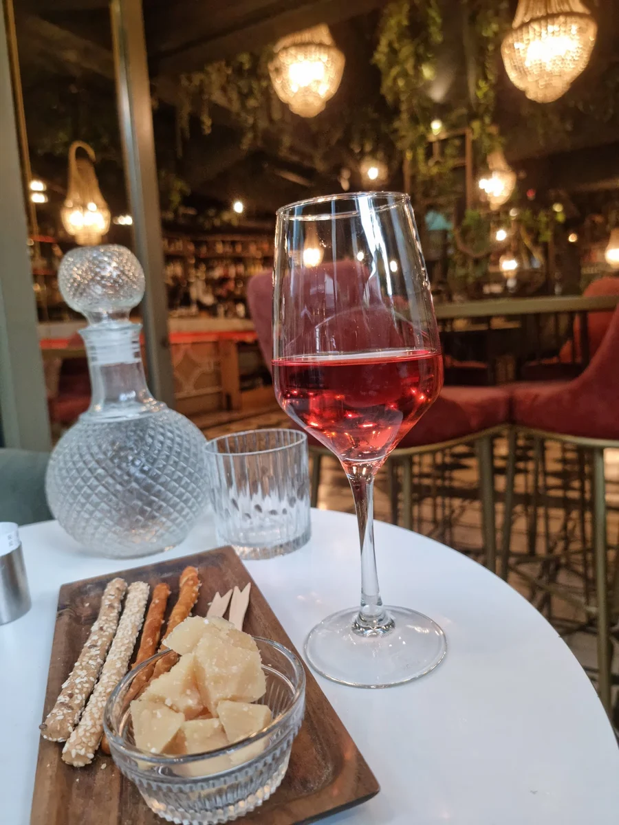 A glass of rosé with a cheese and breadstick board at Chilai wine bar, under chandeliers in Ladadika, Thessaloniki