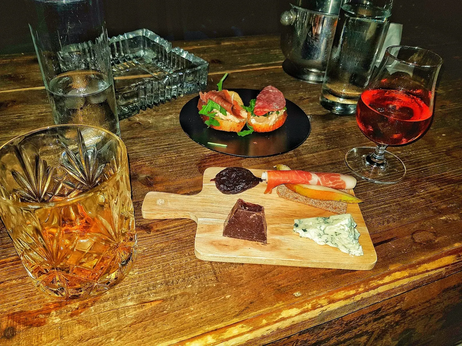 Glasses of red and white wine on a small wine-bar table with cheese and charcuterie