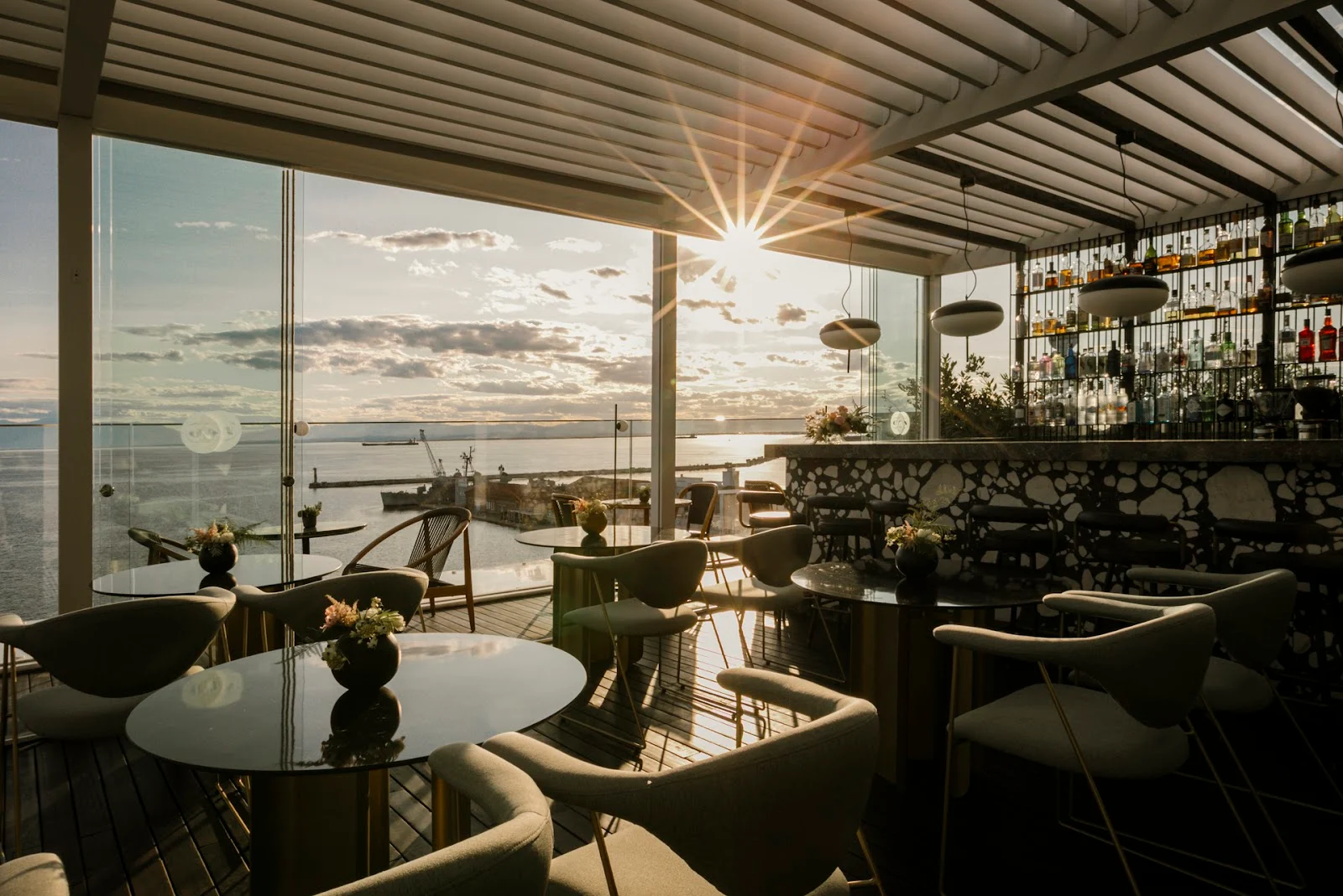 The glass-walled lounge and terrace of ON Rooftop bar overlooking the Thermaic Gulf at golden hour, Thessaloniki