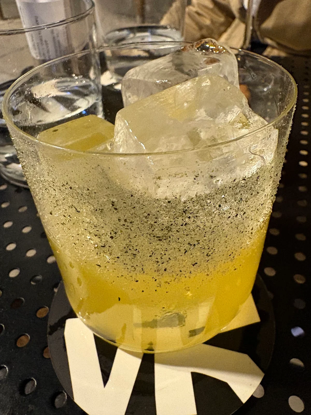 A tall signature cocktail with ice and garnish at Purovōku Project cocktail bar in the Karipi arcade, Thessaloniki