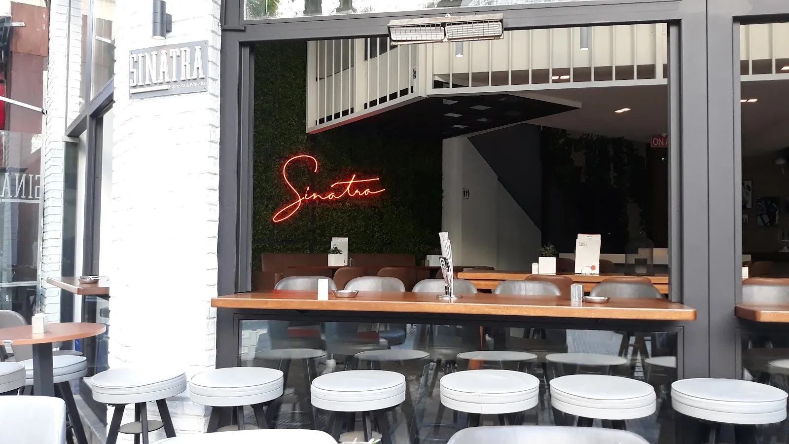 The neon 'Sinatra' script and pavement stools at Sinatra espresso and wine bar on Mitropoleos, Thessaloniki