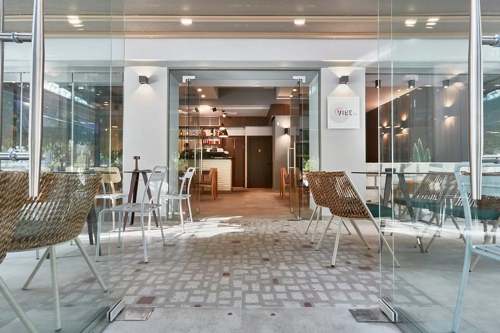 The glass-fronted, minimalist interior and woven-chair terrace of Vibe all-day bar near Navarinou, Thessaloniki
