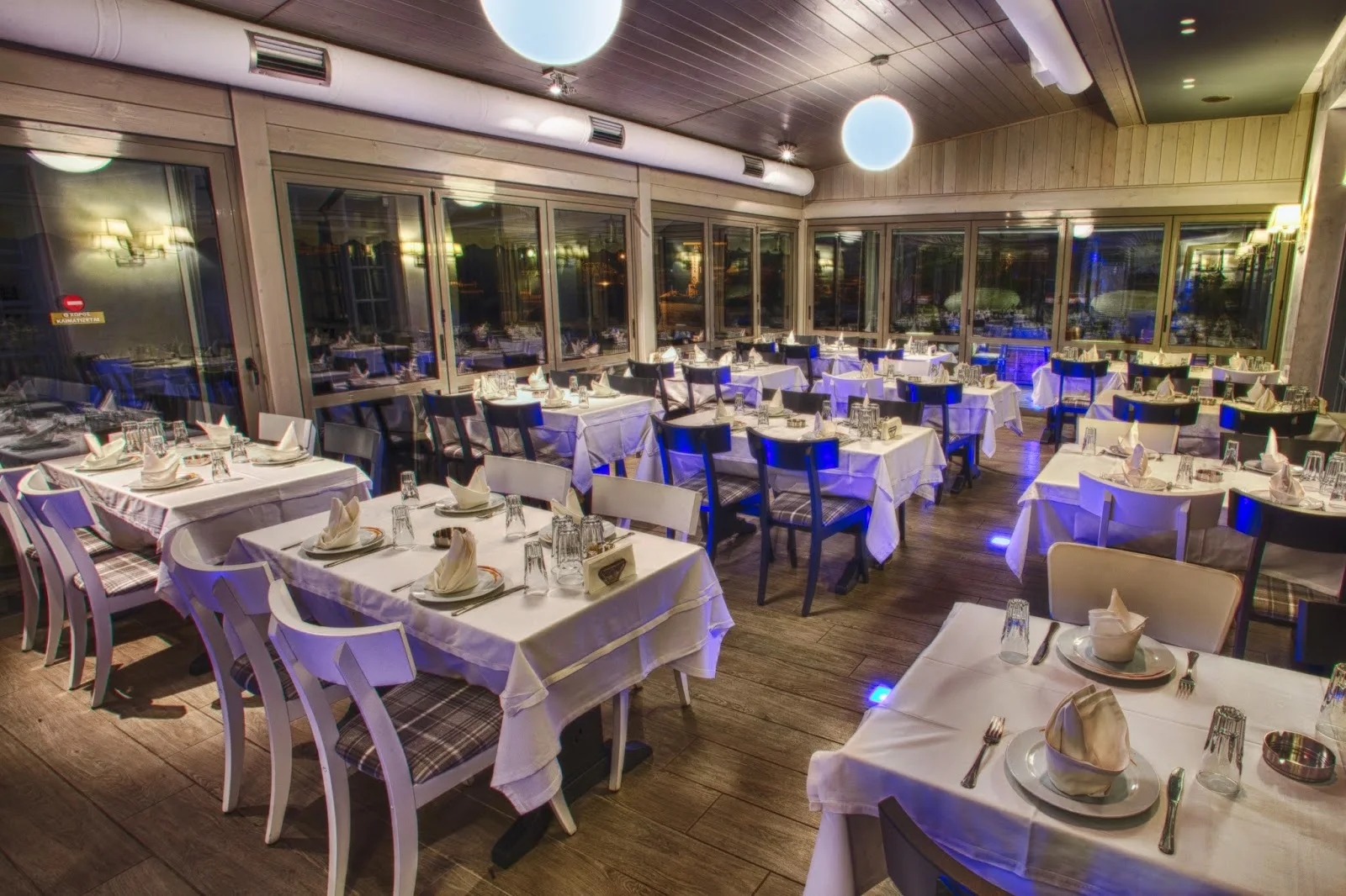 The white-tablecloth dining room of Gialos fish tavern with blue accent lighting, on the Kalamaria seafront, Thessaloniki