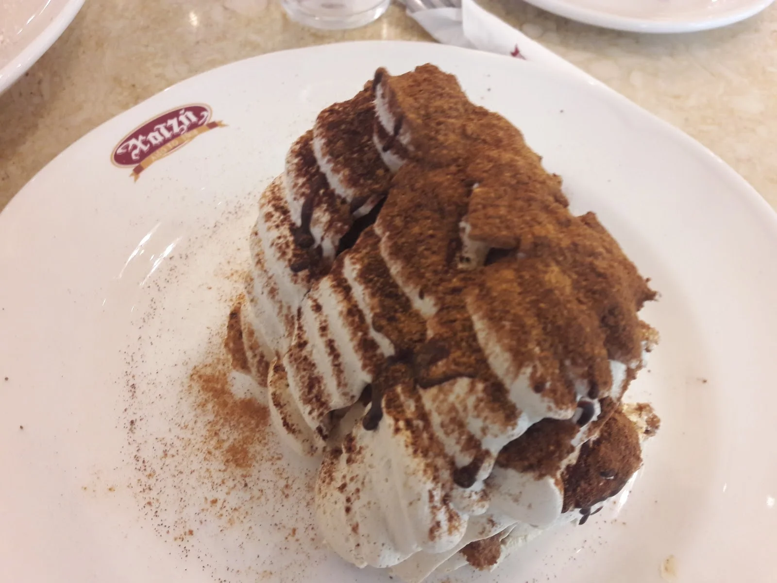 A slice of kazan dipi (caramelised milk pudding) on a Hatzis-branded plate, Thessaloniki