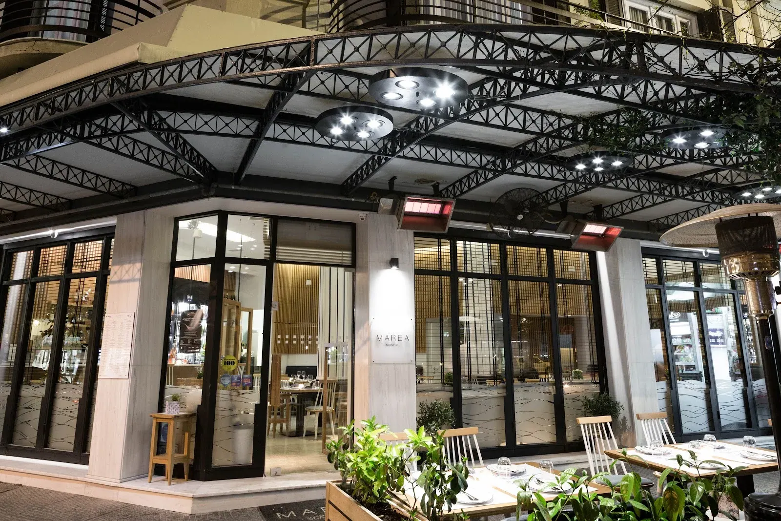 The modern industrial frontage of Marea Sea Spirit seafood restaurant lit up at night, Thessaloniki