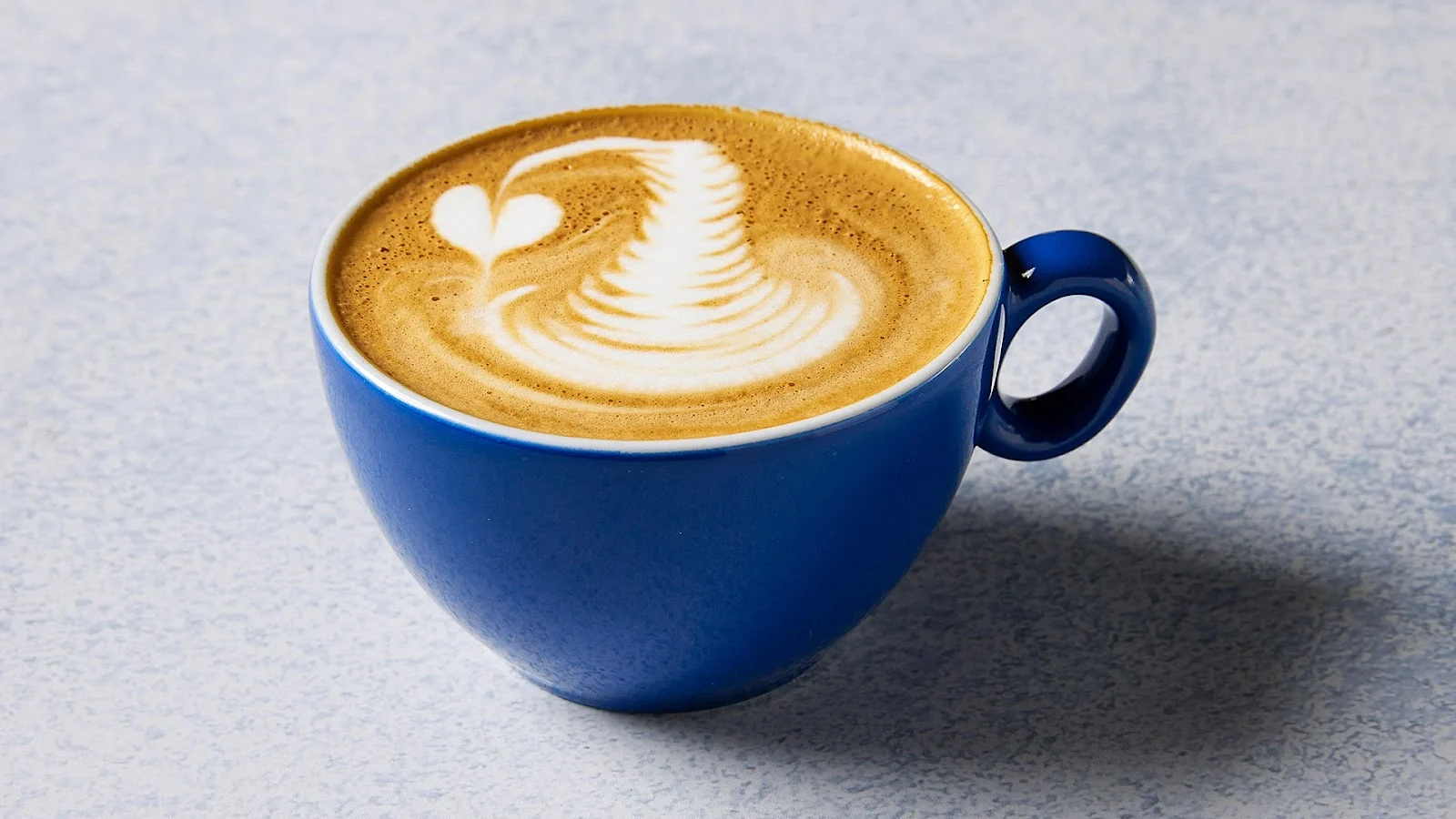 A flat white with rosetta latte art in The Blue Cup's signature blue cup, Thessaloniki