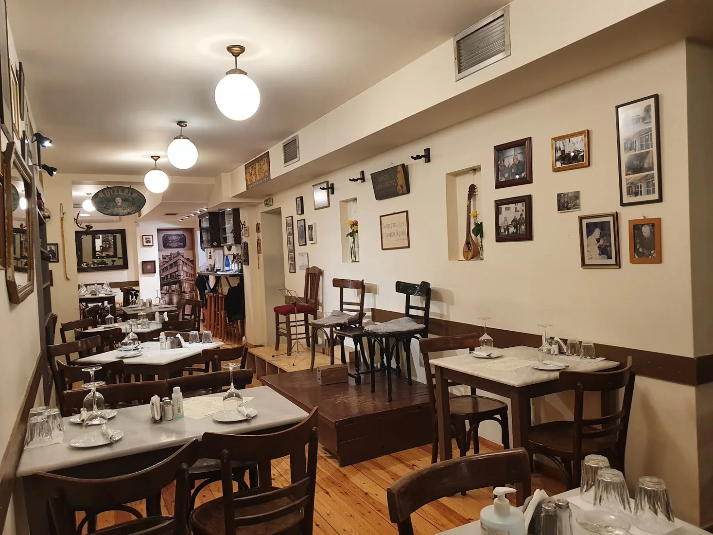 The cosy interior of Tompourlika hung with framed photographs above marble-topped tables, central Thessaloniki